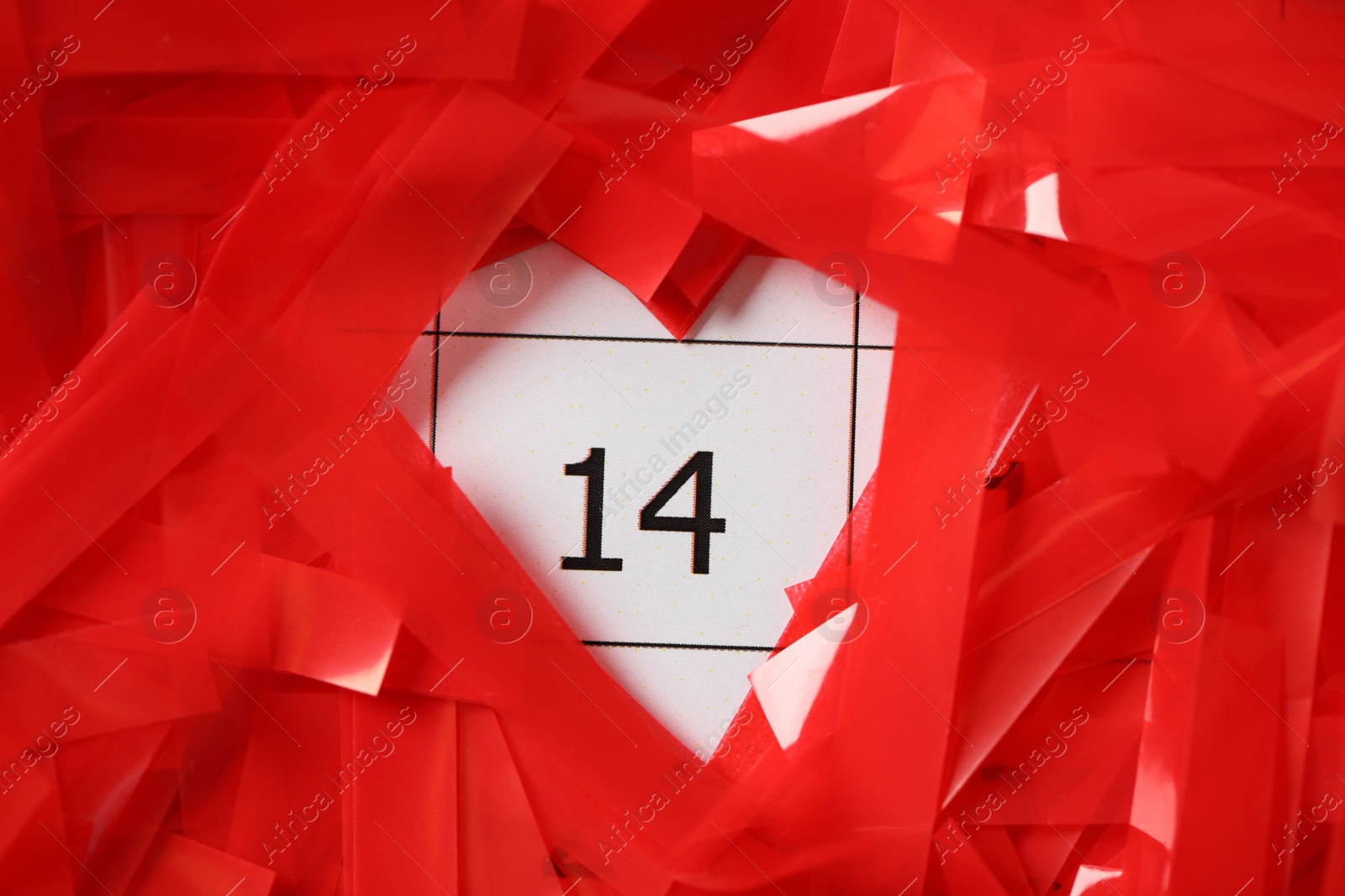 Photo of Red confetti on calendar with number 14, closeup. Valentine's Day celebration