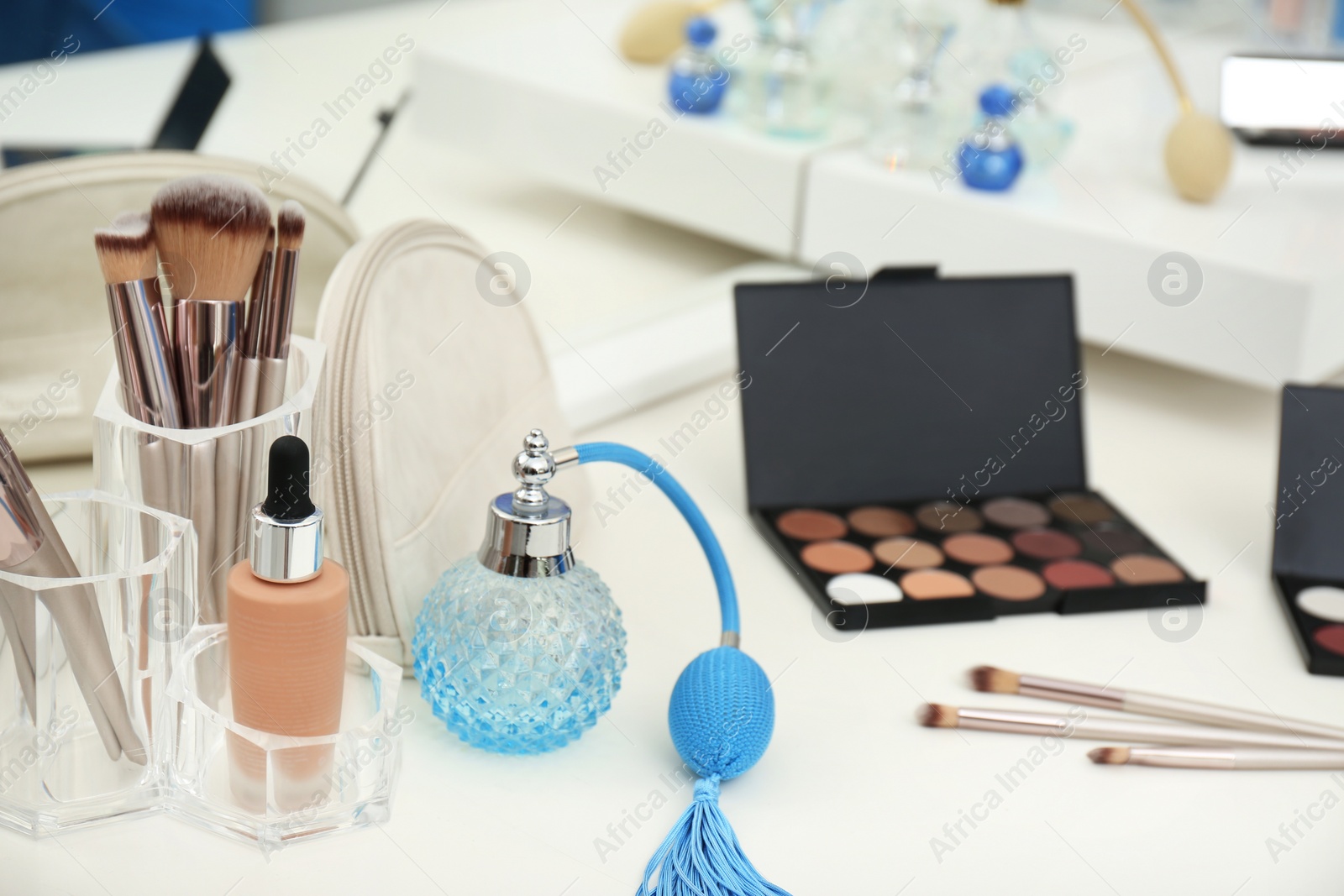 Photo of Different makeup products and bottle of perfume on white dressing table