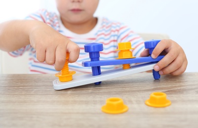 Little boy playing with toy construction tools at wooden table, closeup