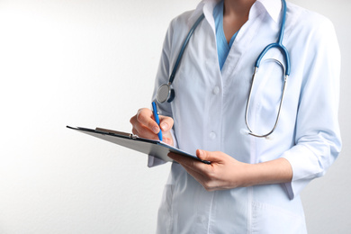 Photo of Doctor with stethoscope and clipboard on white background, closeup. Medical service