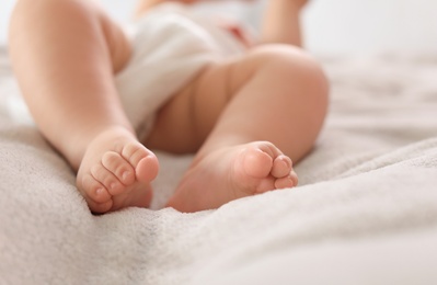 Cute little baby lying on bed, closeup of legs