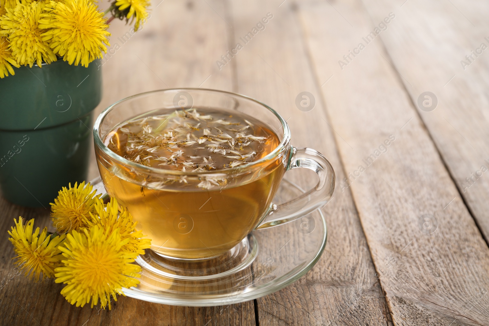 Photo of Delicious fresh dandelion tea on wooden table, closeup. Space for text