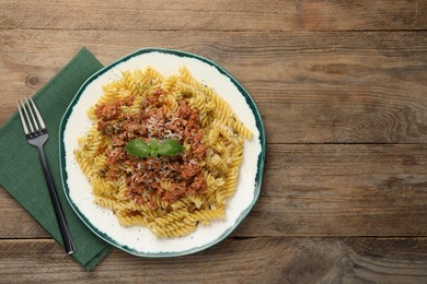 Photo of Delicious pasta with minced meat and basil served on wooden table, flat lay. Space for text