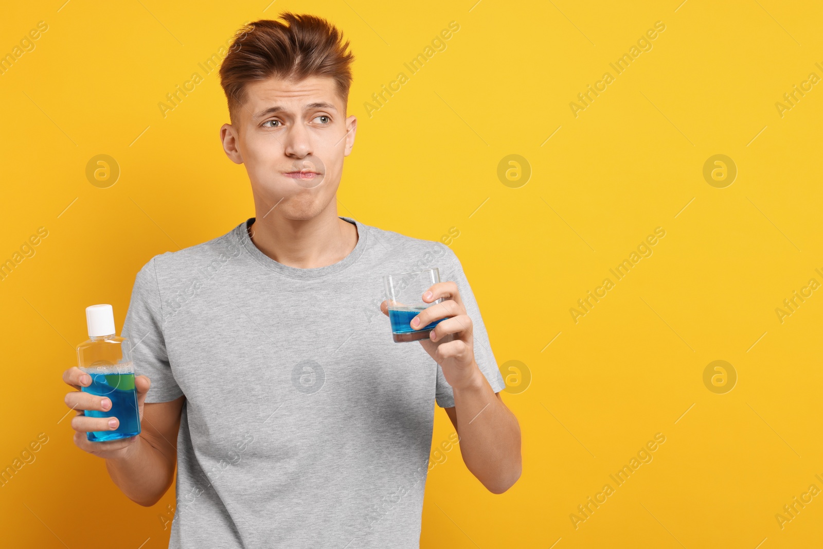 Photo of Young man using mouthwash on yellow background, space for text