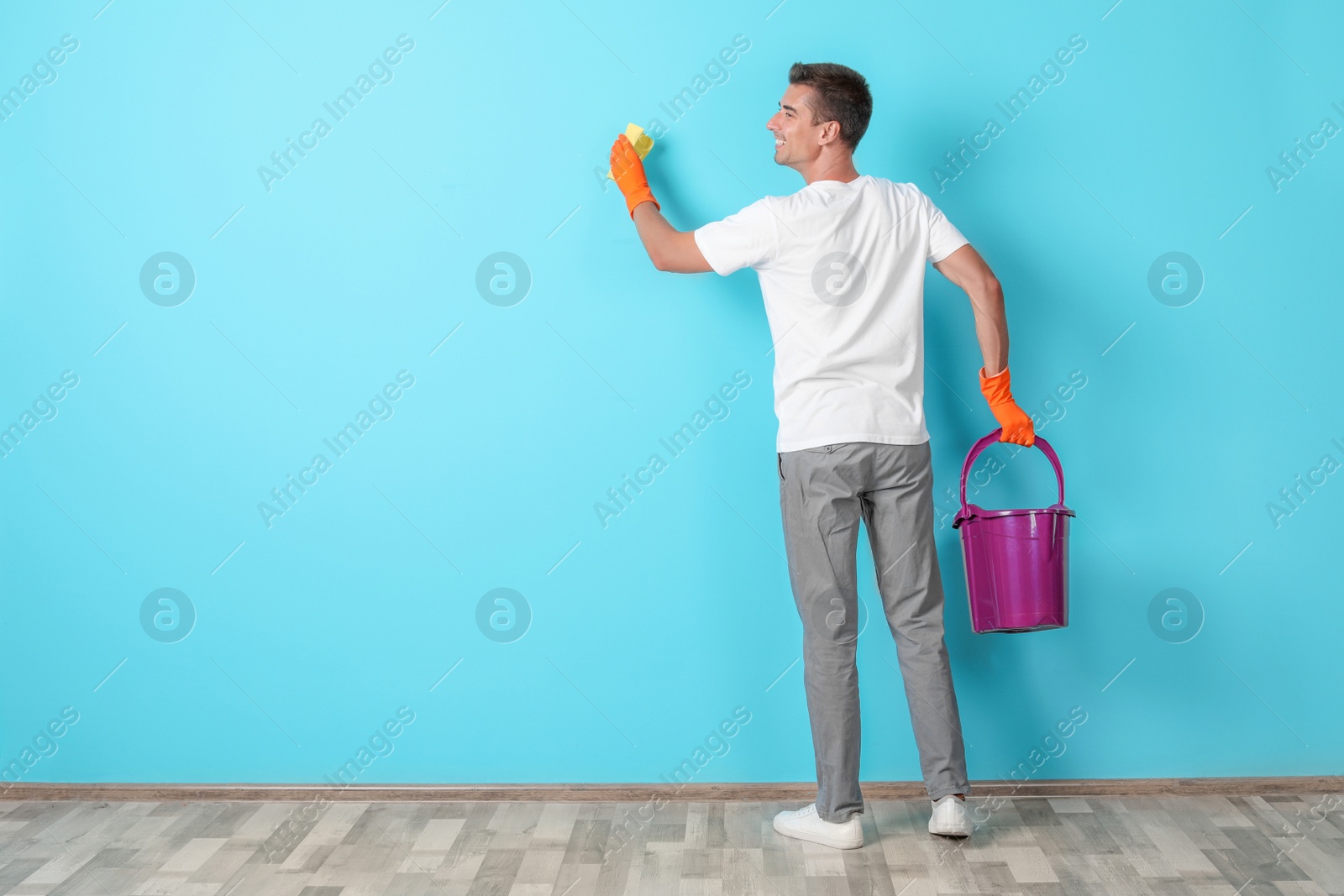 Photo of Man in gloves cleaning color wall with rag