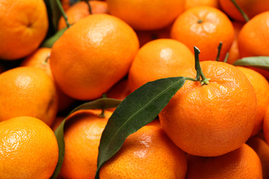 Photo of Fresh ripe tangerines with leaves as background, closeup. Citrus fruit