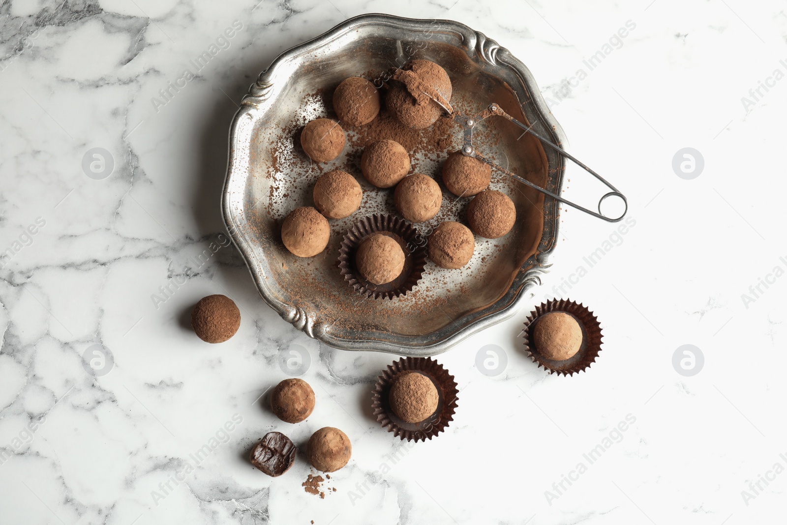 Photo of Plate and tasty chocolate truffles on marble background, top view