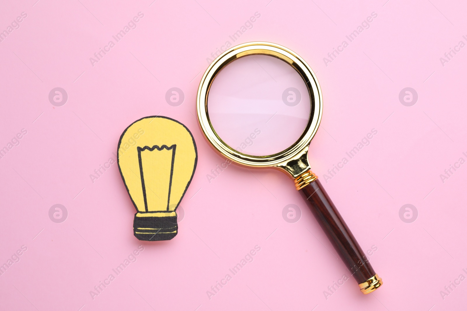 Photo of Magnifying glass and paper light bulb on pink background, flat lay