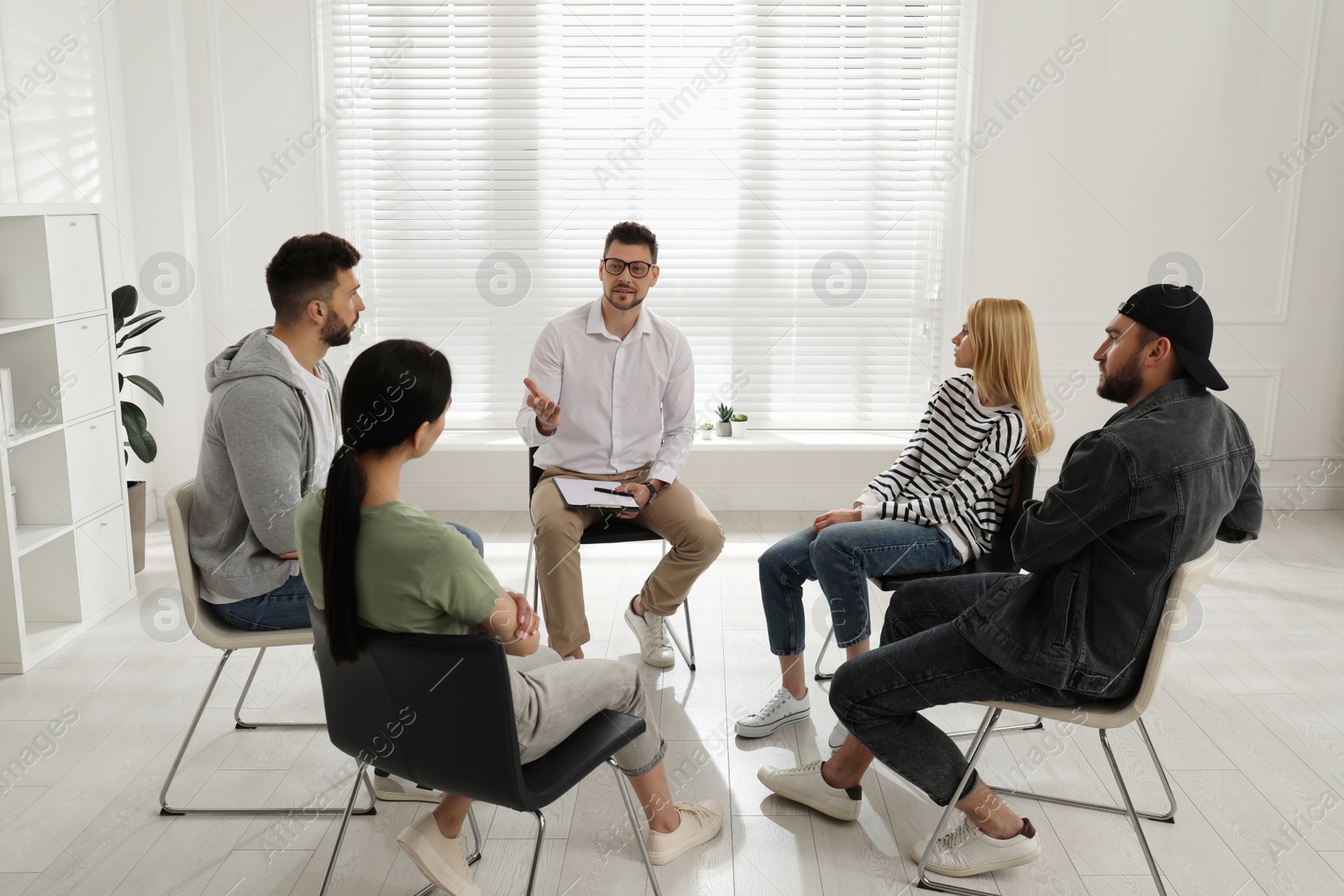 Photo of Psychotherapist working with group of drug addicted people at therapy session indoors