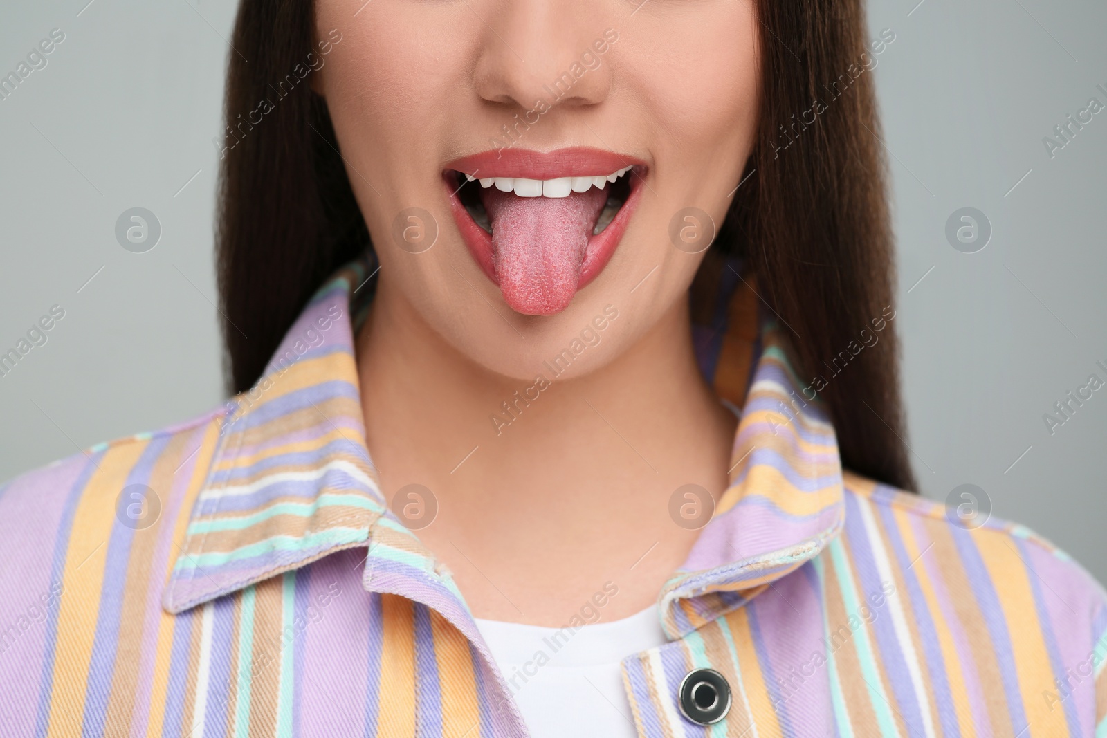 Photo of Woman showing her tongue on gray background, closeup