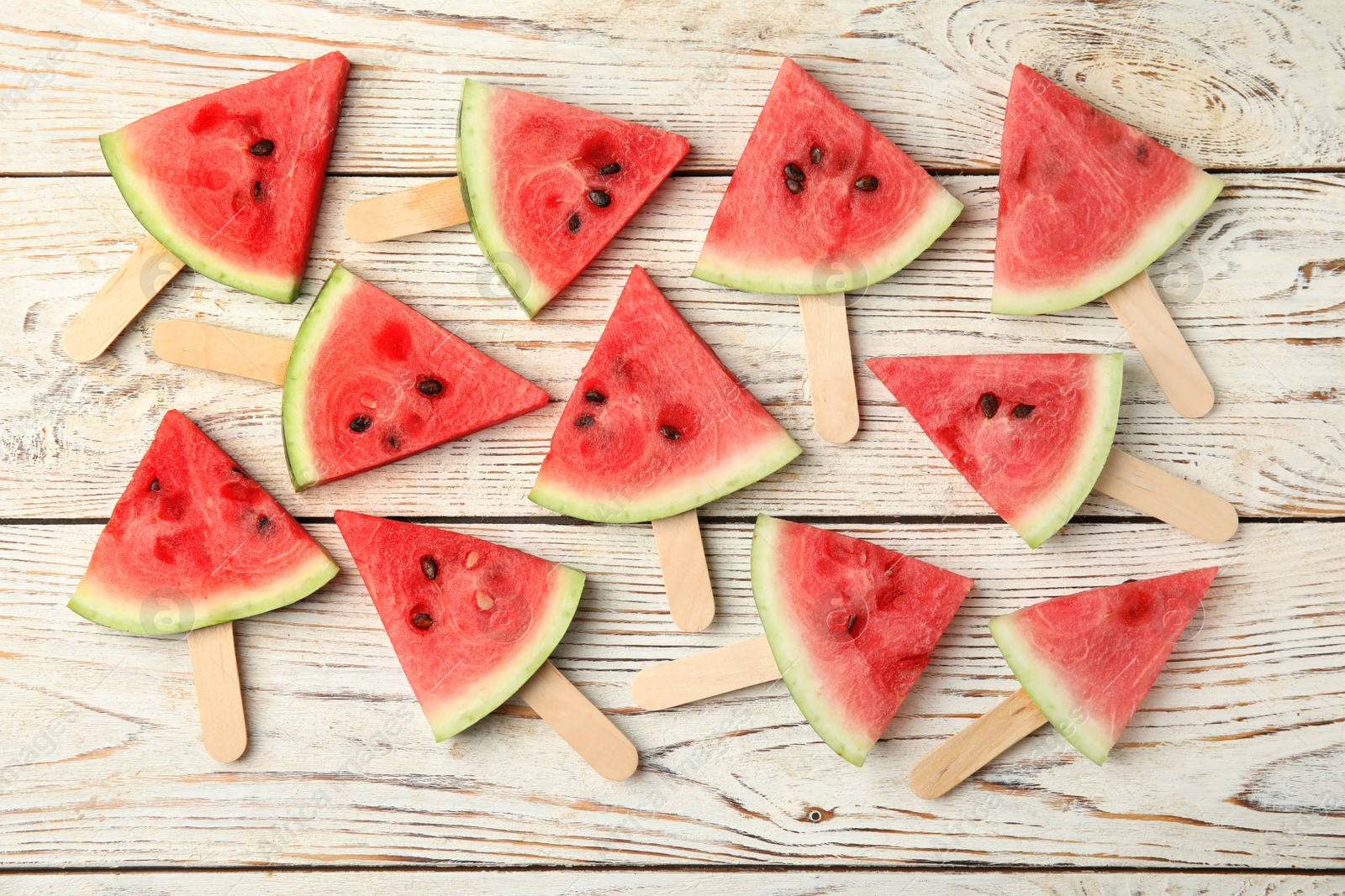 Photo of Slices of ripe watermelon on white wooden table, flat lay