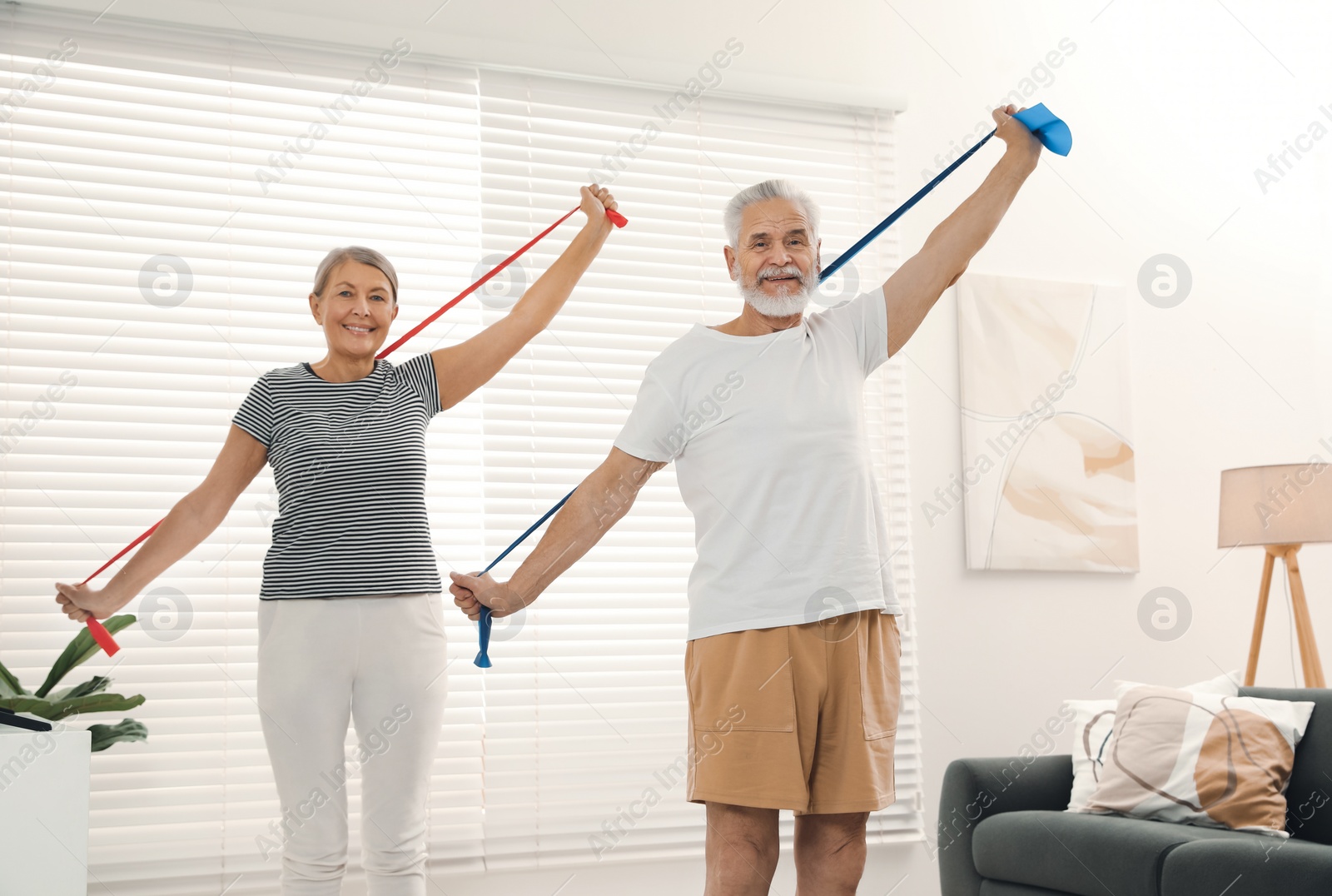 Photo of Senior couple doing exercise with fitness elastic bands at home