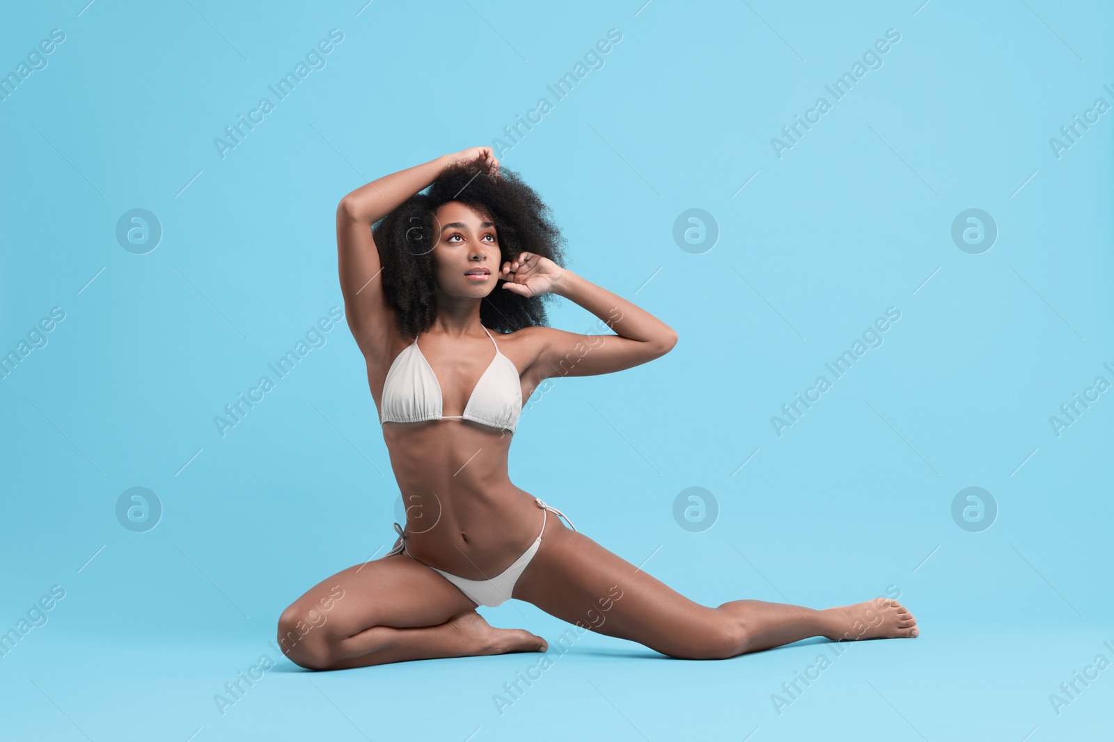 Photo of Beautiful woman in stylish bikini posing on light blue background