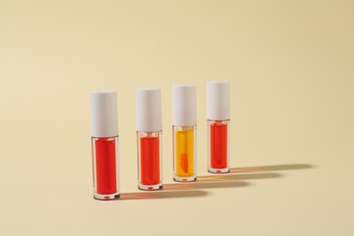 Photo of Many bright lip glosses on beige background