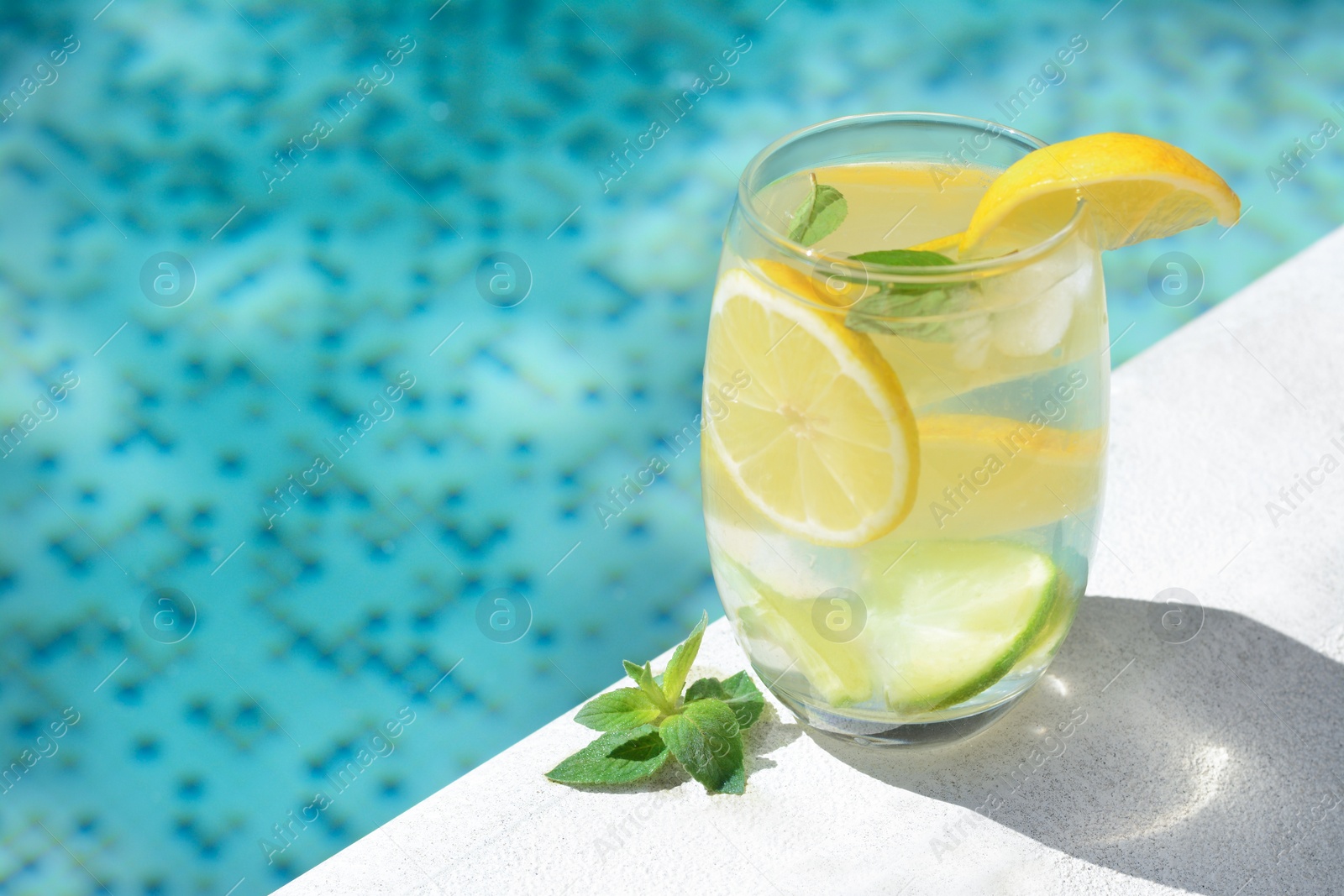 Photo of Refreshing water with lemon slices and mint near swimming pool, closeup. Space for text