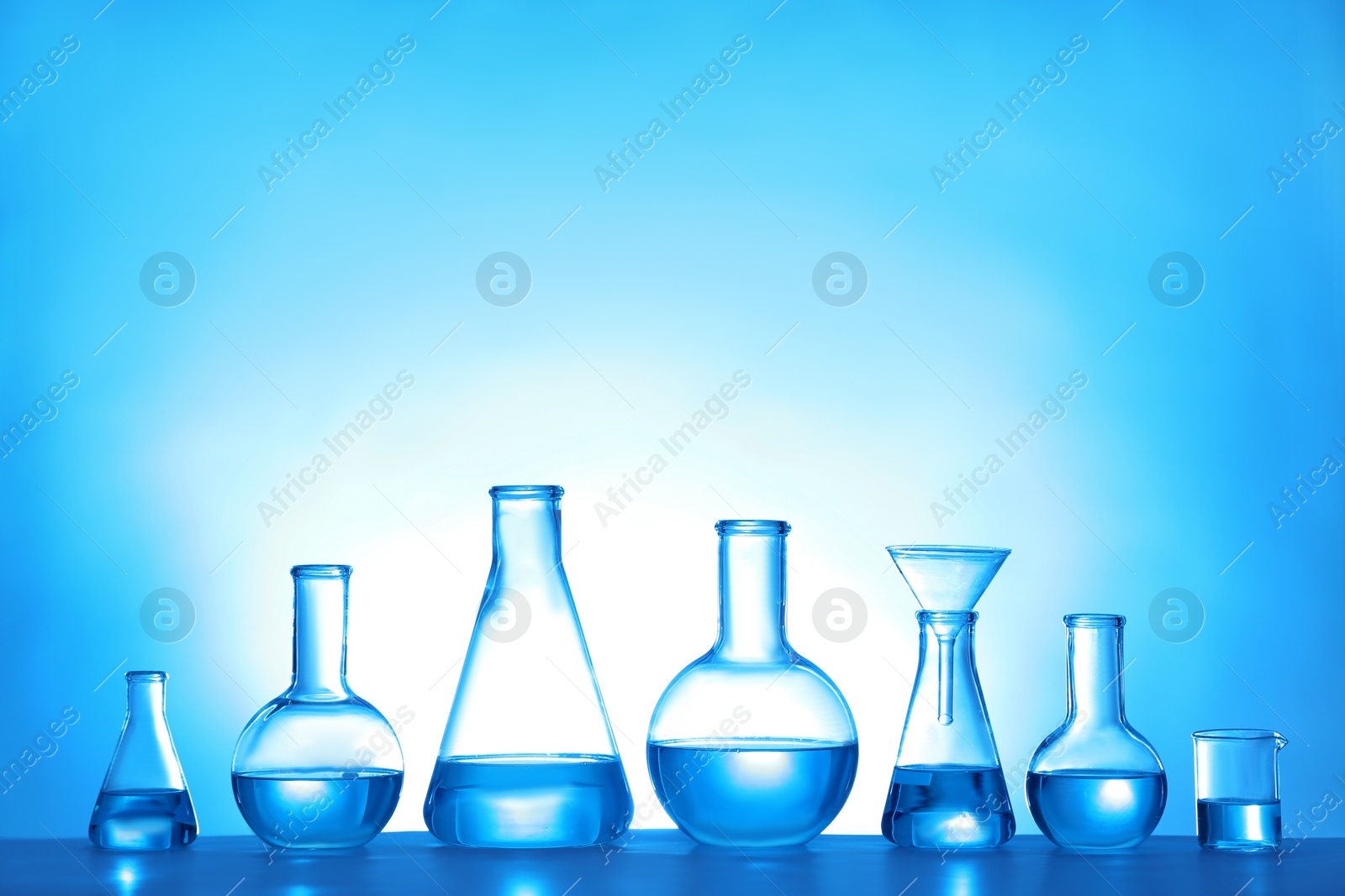 Photo of Laboratory glassware with liquid on color background. Solution chemistry