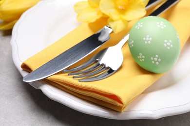 Festive Easter table setting with egg on grey background, closeup