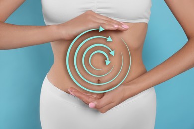 Image of Healthy digestion. Woman with circular arrows on her belly against light blue background, closeup