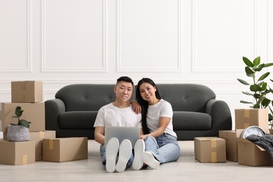 Photo of Happy couple with laptop on floor in their new apartment