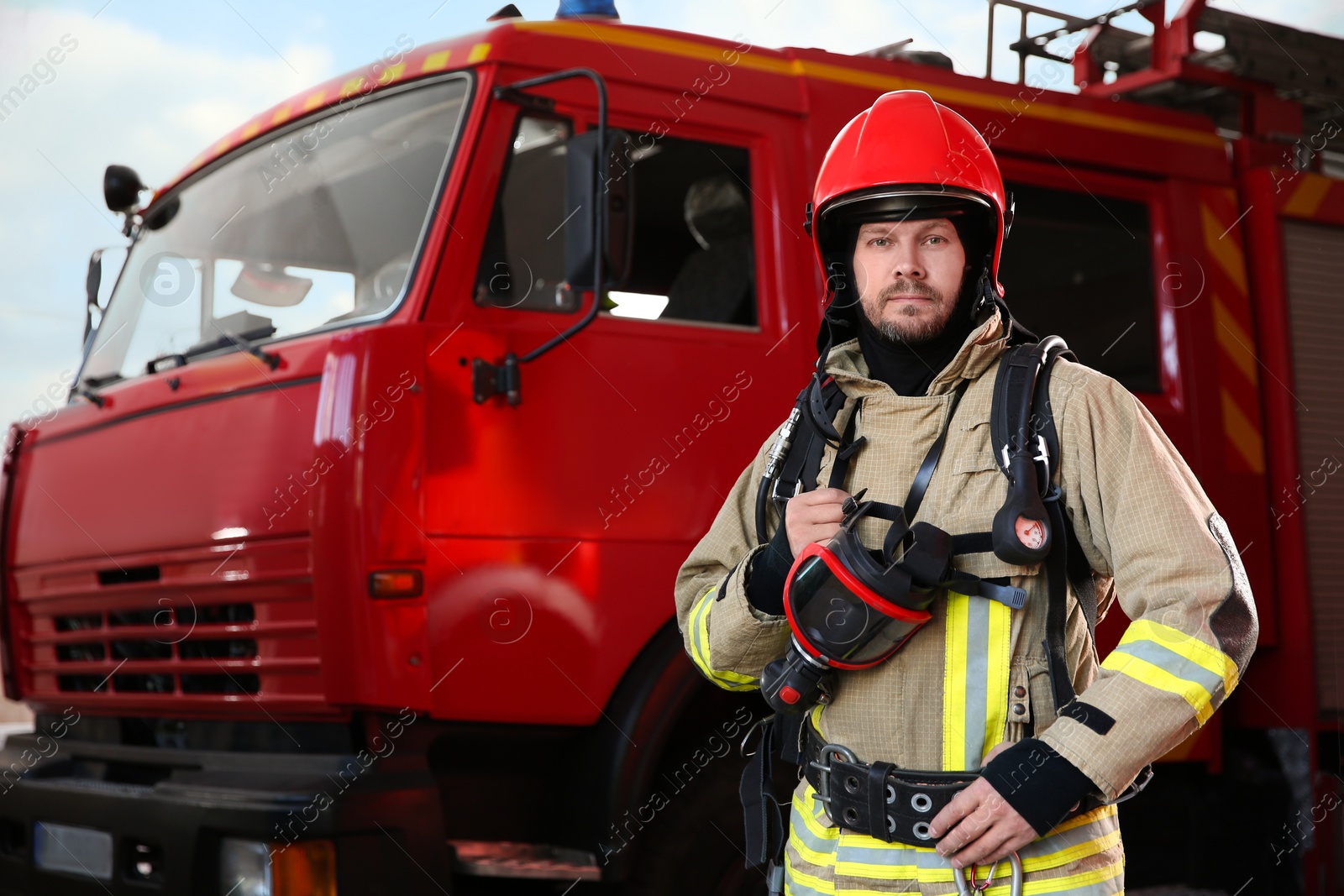 Photo of Firefighter in uniform near red fire truck at station