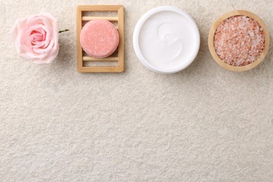 Photo of Flat lay composition with moisturizing cream in open jar and other body care products on light textured table. Space for text