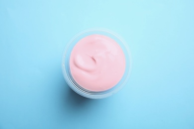 Photo of Plastic cup with creamy yogurt on color background, top view