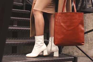 Photo of Woman in stylish leather shoes with bag on stairs outdoors, closeup