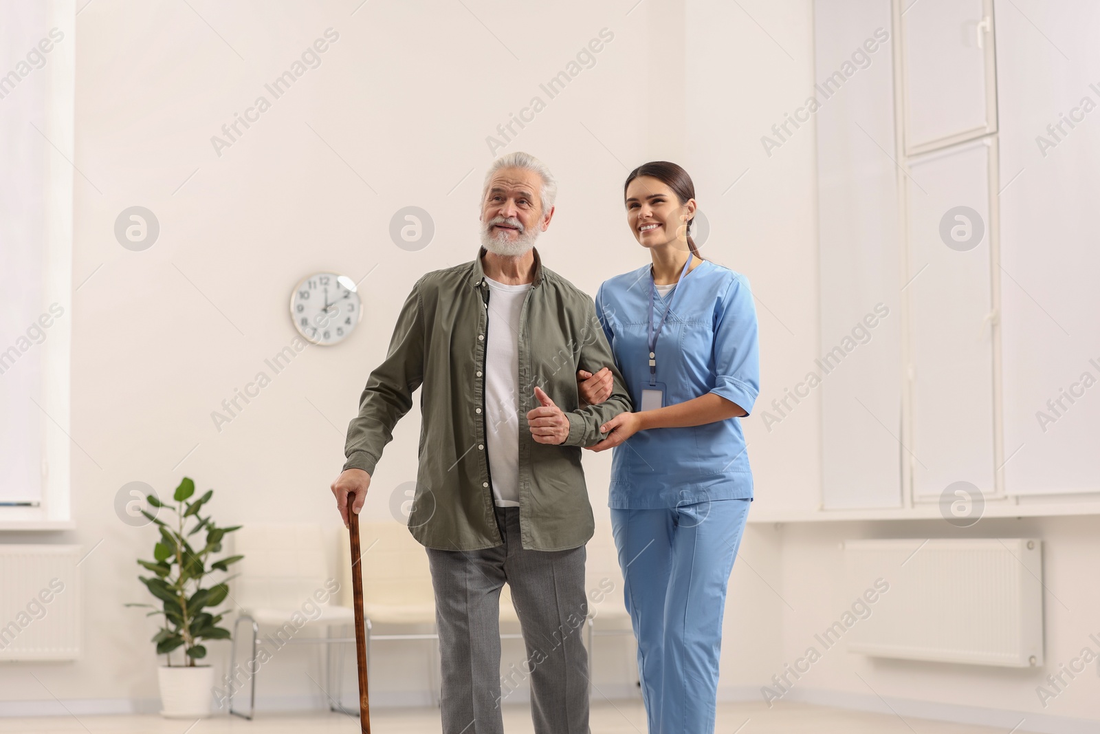 Photo of Smiling nurse supporting elderly patient in hospital