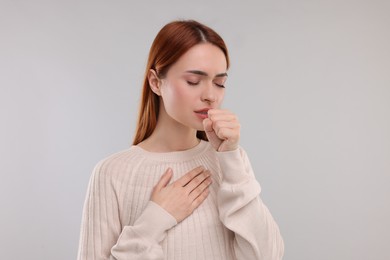 Woman coughing on light grey background. Cold symptoms