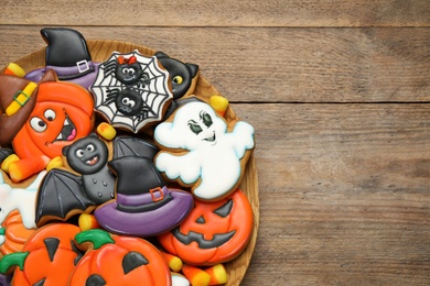 Photo of Tasty cookies and sweets for Halloween party on wooden table, top view. Space for text
