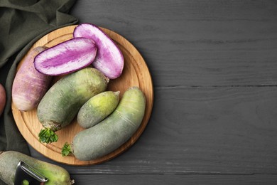 Photo of Green and purple daikon radishes on gray wooden table, top view. Space for text