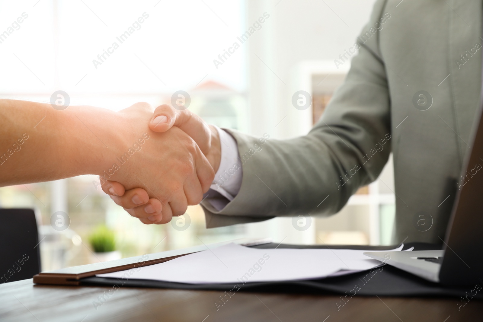 Photo of Business partners shaking hands at table after meeting in office, closeup