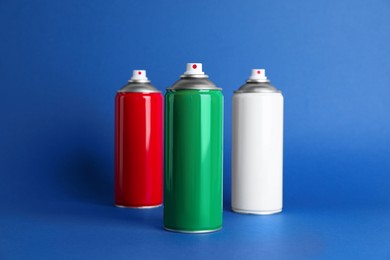 Photo of Colorful cans of spray paints on blue background