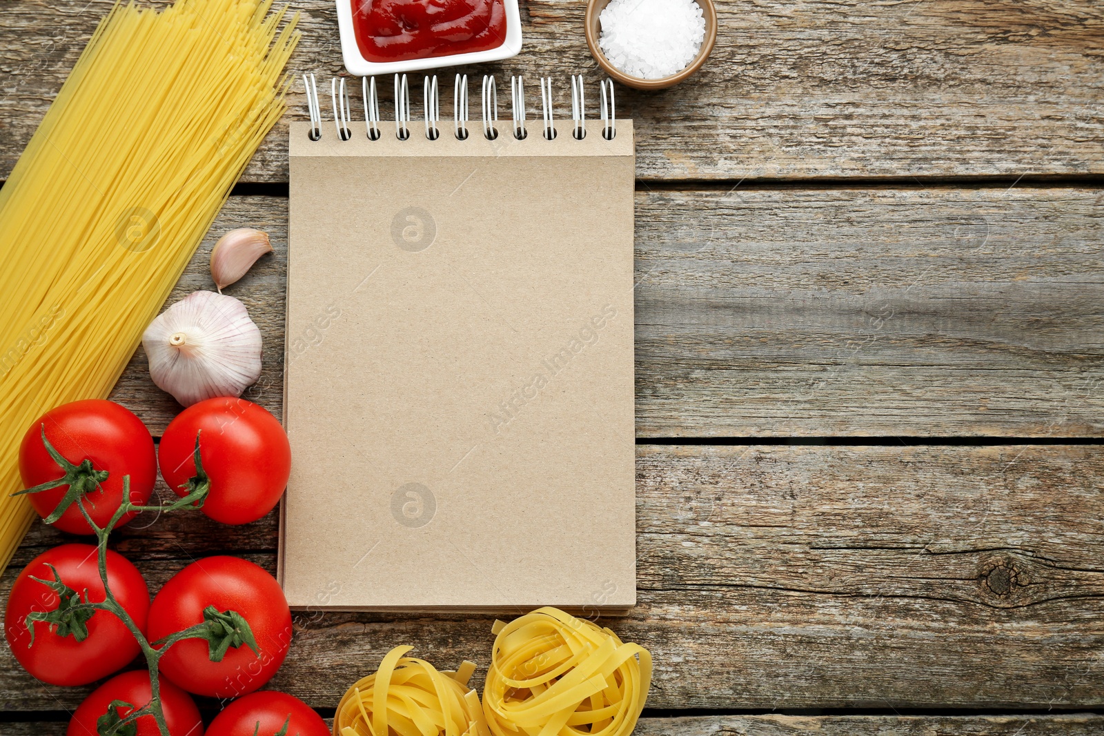 Photo of Blank recipe book and different ingredients on wooden table, flat lay. Space for text