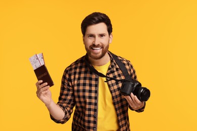 Photo of Smiling man with passport, tickets and camera on yellow background