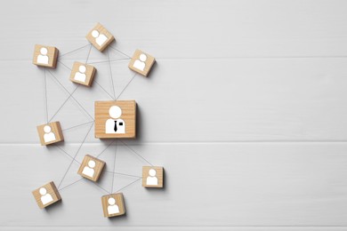 Image of Team management. Cubes with human icons linked together symbolizing company structure on white wooden table, top view. Space for text
