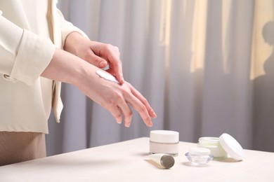 Woman applying hand cream at home, closeup