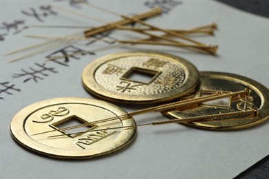 Photo of Acupuncture needles, Chinese coins and paper with characters on table, closeup