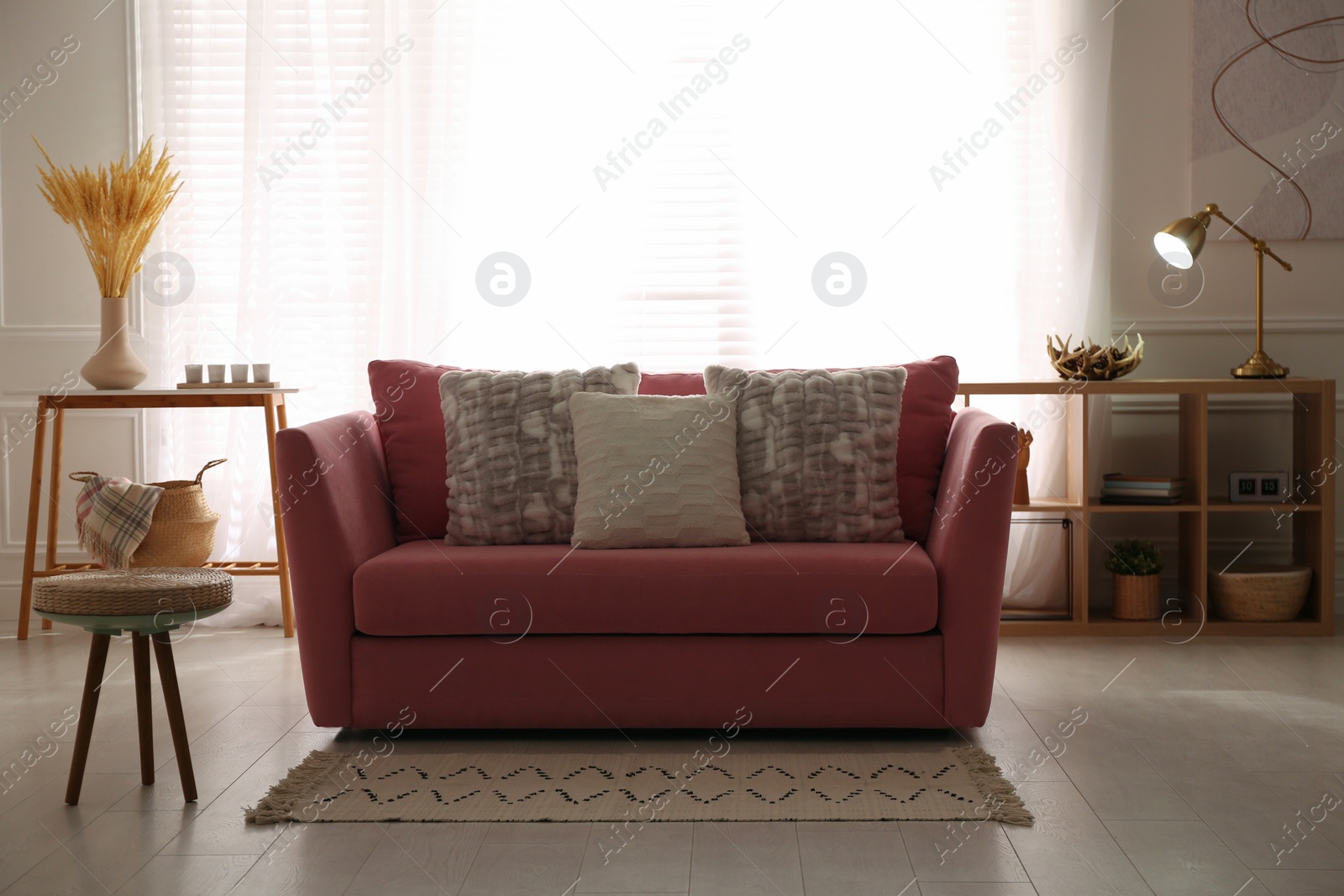Photo of Stylish living room interior with comfortable red sofa and cushions
