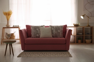 Stylish living room interior with comfortable red sofa and cushions