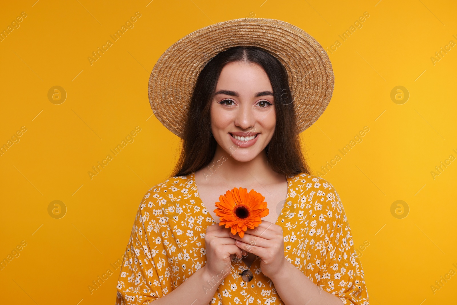 Photo of Beautiful woman with spring flower in hands on yellow background