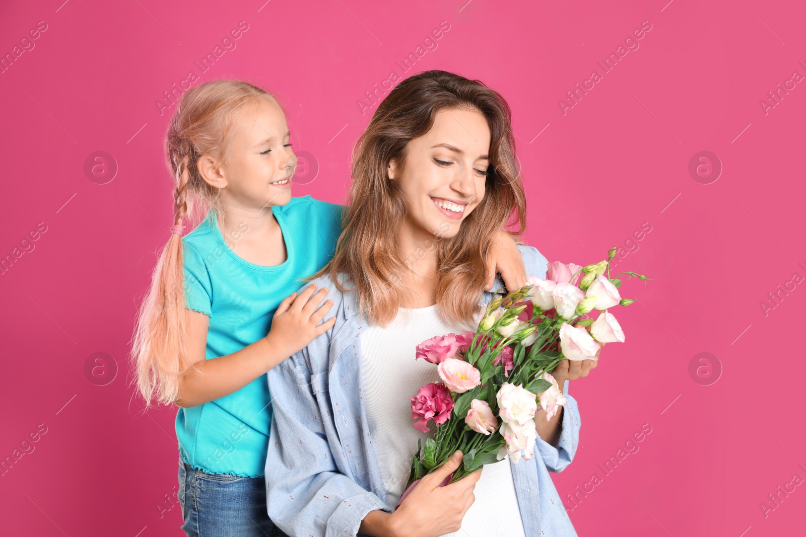 Photo of Little daughter congratulating her mom on pink background. Happy Mother's Day