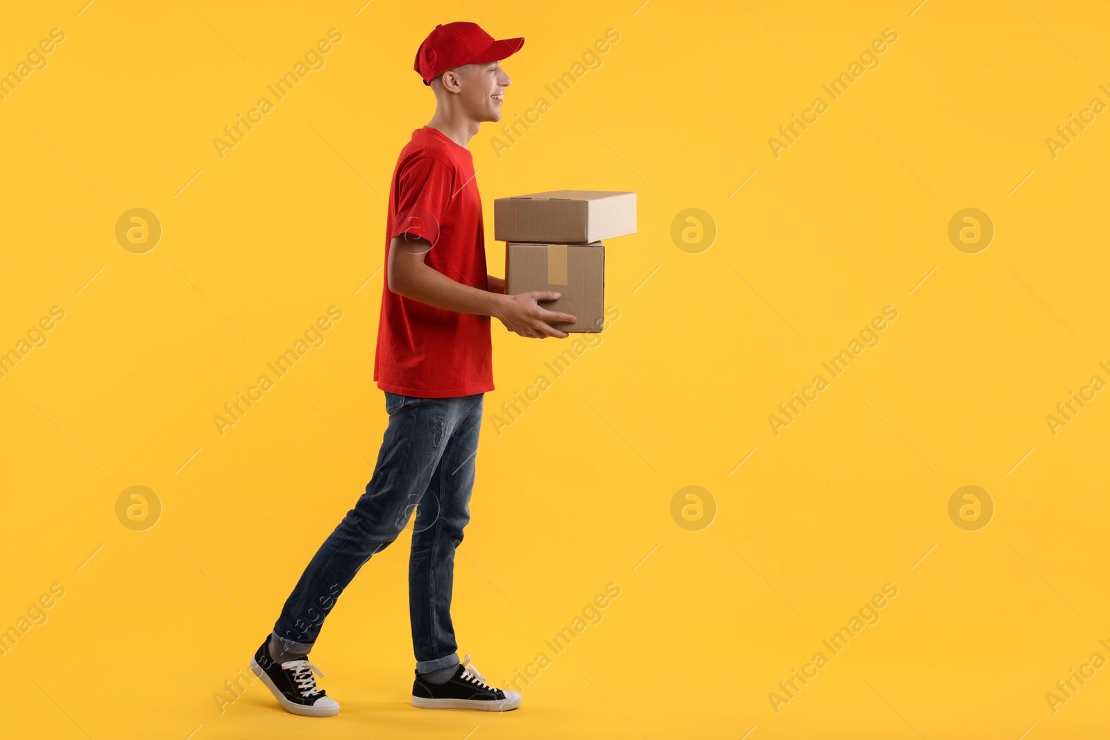 Photo of Happy courier with parcels on yellow background. Space for text