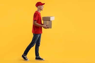 Photo of Happy courier with parcels on yellow background. Space for text