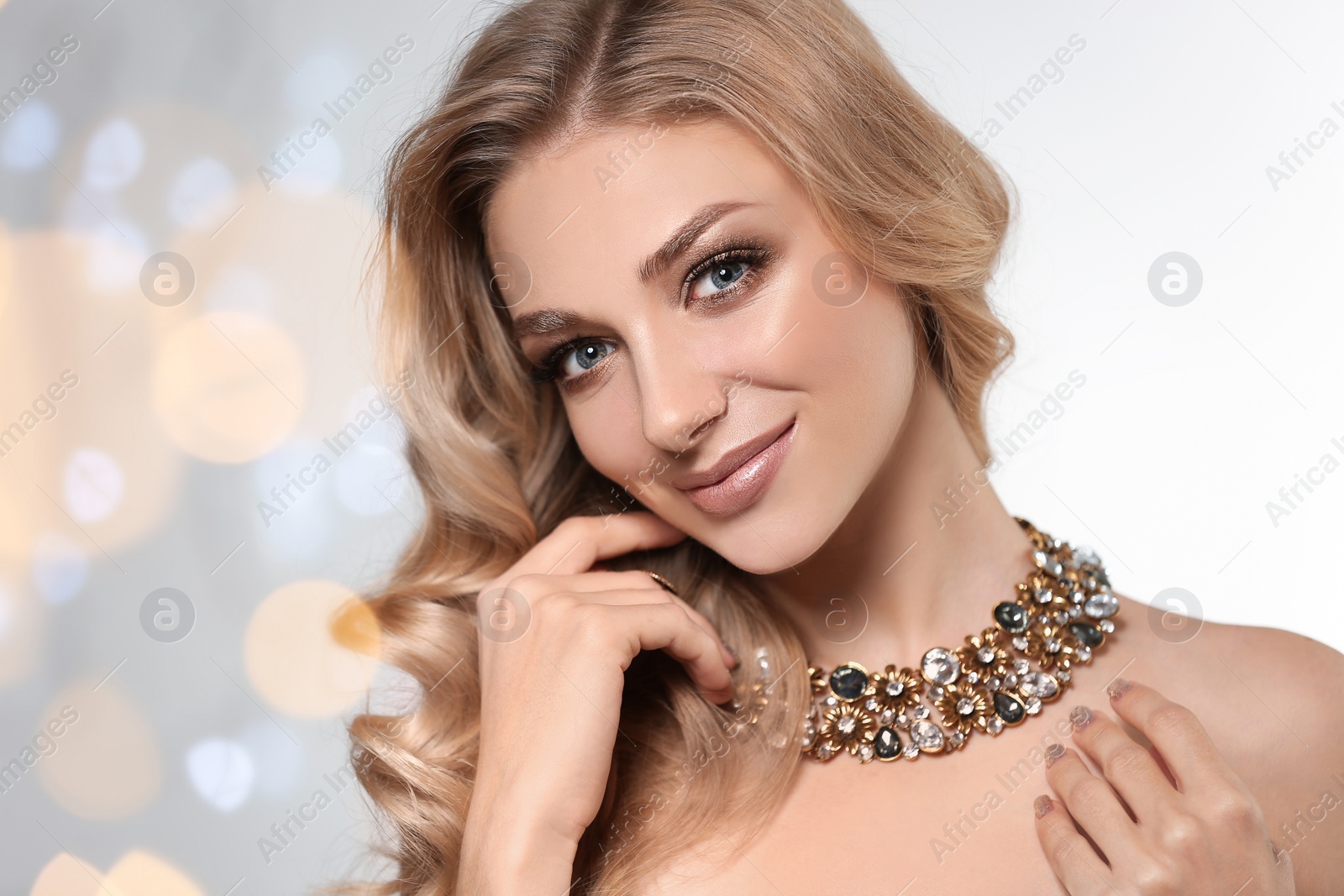 Photo of Beautiful young woman with elegant jewelry against defocused lights. Space for text