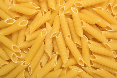 Photo of Uncooked penne pasta as background, top view