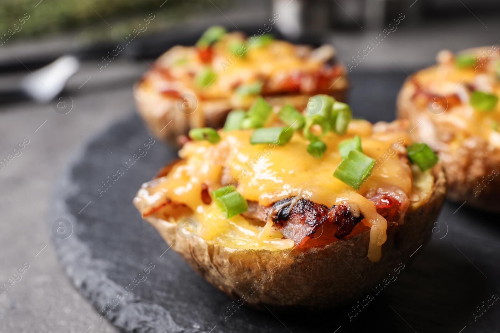 Photo of Slate plate with baked potatoes on table, closeup