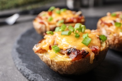 Photo of Slate plate with baked potatoes on table, closeup