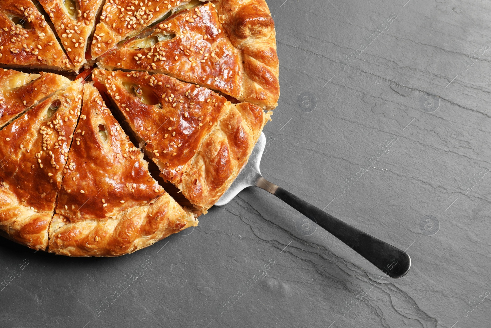 Photo of Cut delicious homemade pie and server on black table, top view