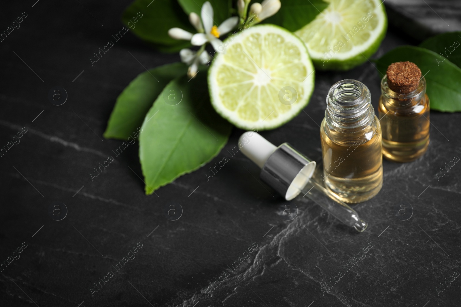 Photo of Bottles of citrus essential oil on black table. Space for text